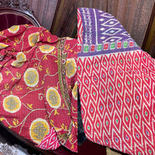 red blanket with yellow and white flowers in a circle with purple green diamond shapes 