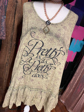 mannequin with a yellowish brown tank that says pretty is as pretty does partnered with a real stone and gold necklace with cream beads