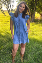girl in blue short sleeve denim dress  and brown boots with green background