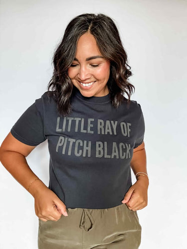 Woman wearing a black t-shirt with text, smiling against a plain background