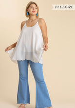 Woman wearing a white top and blue jeans on a beige background with 'Plus Size' text.