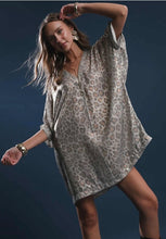 Woman wearing a patterned dress against a dark background leopard print