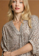 Woman wearing a patterned blouse against a brown background leopard print