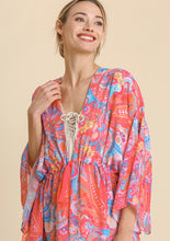 Woman wearing a colorful patterned dress on a beige background