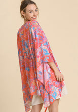 Woman wearing a colorful patterned kimono-style garment on a beige background