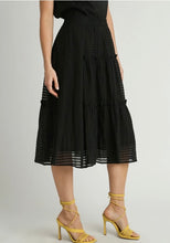 Person wearing a black skirt with sheer panels on a plain background