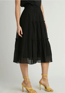 Person wearing a black skirt with sheer panels on a plain background
