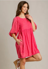 Woman wearing a pink dress against a plain background