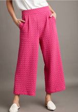 Person wearing pink textured pants on a gray background