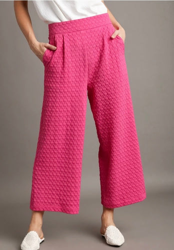 Person wearing pink textured pants on a gray background