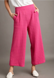 Person wearing pink textured pants on a gray background