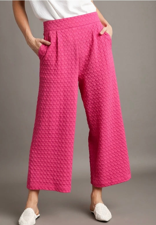 Person wearing pink textured pants on a gray background