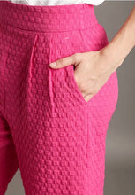 Close-up of pink textured pants with a neutral background