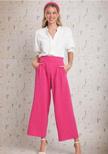 Woman wearing a white blouse and pink pants against a light background