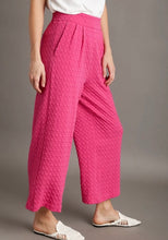 Person wearing pink textured pants on a gray background