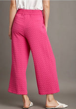 Person wearing pink textured pants on a gray background