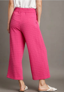 Person wearing pink textured pants on a gray background