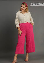 Woman wearing a beige blouse and pink textured pants on a gray background with 'Plus Size' text.
