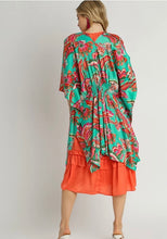 Woman wearing a colorful patterned jacket over an orange dress on a plain background