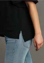 Person wearing a black top and light blue jeans on a gray background