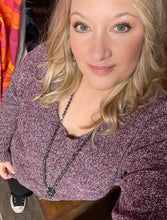 Woman with blonde hair wearing a purple textured sweater v neck long sleeves