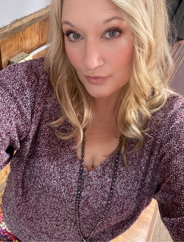 Woman with blonde hair wearing a purple textured sweater v neck long sleeves