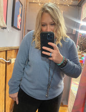 Person taking a mirror selfie wearing a blue sweater in an indoor setting.