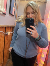 Person taking a mirror selfie wearing a blue textured sweater in a room with colorful decor.
