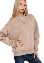 Woman wearing a beige zip-up sweatshirt on a white background