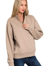 Woman wearing a beige half-zip sweatshirt on a white background