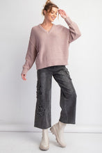 Woman wearing a mushroom colored sweater and gray pants on a white background