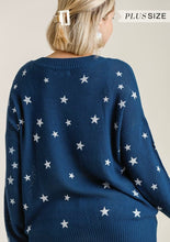 Navy blue sweater with white star patterns worn by a person, on a plain background.