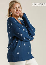 Woman wearing a blue sweater with star patterns on a plain background