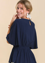 Woman wearing a navy blue dress with a beige background