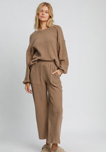 Woman wearing a brown ribbed knit outfit on a light gray background