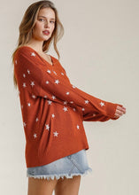 Woman wearing a rust-colored sweater with star patterns on a beige background