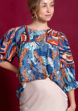 Woman wearing a colorful patterned blouse against a red background
