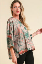 woman wearing a tan and green satin top against a tan background short sleeves