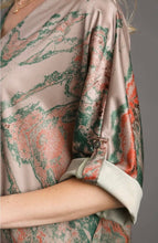 woman wearing a tan and green satin top against a gray background short sleeves