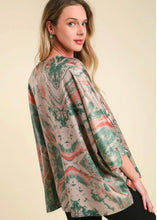 woman wearing a tan and green satin top against a tan background short sleeves