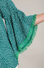 Green patterned fabric with frayed edge on a neutral background