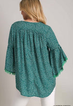 Green patterned blouse worn by a person on a plain background