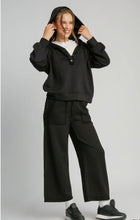 Person wearing a black hoodie and pants on a gray background