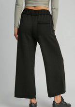 Person wearing black checkered pants on a plain background