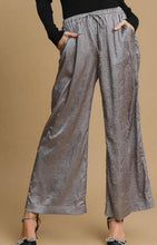 Silver metallic wide-leg pants worn by a person on a beige background