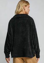 Person wearing a black sweater on a plain background