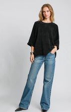 Woman wearing a black sweater and blue jeans on a white background