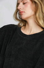 Person wearing a black sweater against a plain background
