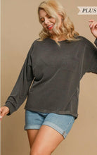 Woman wearing a dark ribbed sweater and denim shorts on a beige background