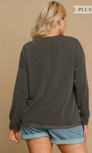 Woman wearing a dark ribbed sweater and denim shorts on a beige background